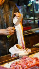 Obraz premium Butcher expertly slicing raw meat at a bustling market
