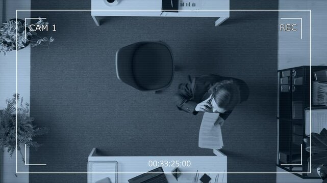 Security camera video from above of nervous male manager dressed in suit leaving his seat at table and moving around with documents during intense phone call