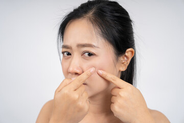Asian woman squeezing pimples on her face, skin care lifestyle concept.