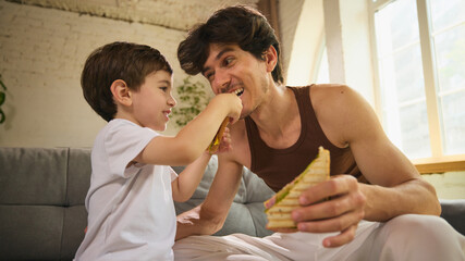 Family moments. A Caucasian father and son share a joyful breakfast, filled with laughter,...