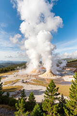 Fototapeta premium Geothermal area landscape with erupting geysers in scenic park environment. Geothermal area surrounded by forest against blue sky creates an impressive vista with erupting hot springs.