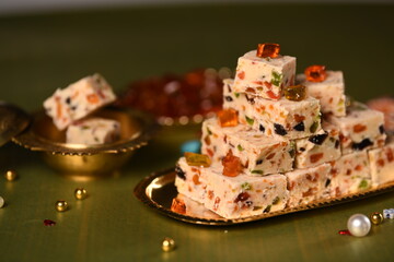 malai barfi with tutti frutti in golden flats on green background