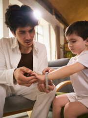 Timeless style. Dad assists his child with a smartwatch during an indoor bonding moment. Depiction...