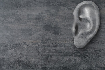 Human ear in grey stone wall, space for text. Eavesdropping, concept that even walls have ears