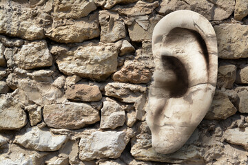 Human ear in old stone wall, space for text. Eavesdropping, concept that even walls have ears