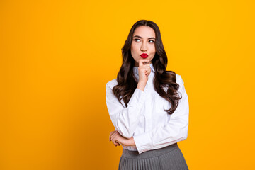 Stylish young woman in a formal outfit thinking, with a bright yellow background highlighting her...