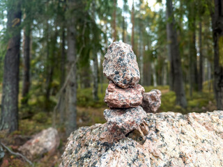 Pyramid of rocky stones natural balance in the summer forest. Stone pyramid. Forest background.
