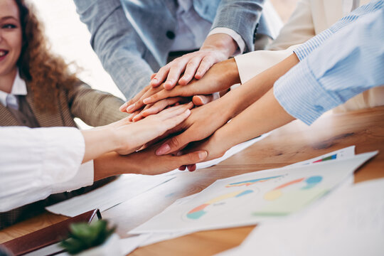 Office team collaboration symbolizing unity and teamwork with business colleagues joining hands during a professional meeting