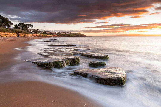 Sunrise view over the ocean with rocky shoreline and gentle waves