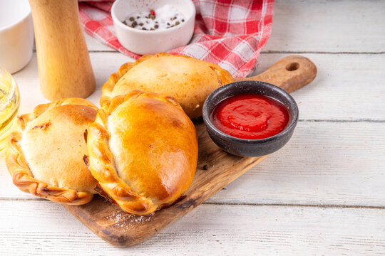 Homemade golden baked hand pies, with filling. Italian closed pizza calzone, empanadas, pierogies. Mini puff pastry or hand pies filled with sweet or savory stuffing. 