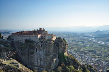 Meteora&rsquo;s monasteries perch on rocky cliffs, lit by soft afternoon winter sun, blending nature and history in peaceful harmony.
