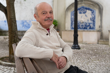 Elderly Spanish Man Sitting on a Bench in the Shade of Trees and Resting
