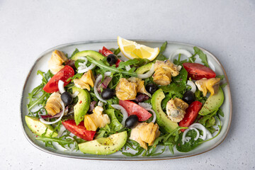 Warm salad with rapans (snails), tomatoes, avocado, arugula, black olives, onions and olive oil. Traditional seafood salad. Close-up, selective focus.