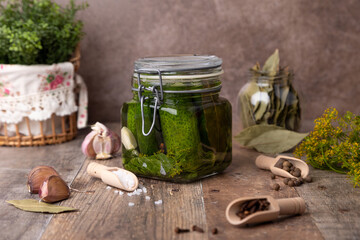 Half-sour dill pickle (quick pickled cucumbers) in a jar with seasonings, spices and herbs. Homemade seasonal preparations. Traditional canning of vegetables. Selective focus, close-up.