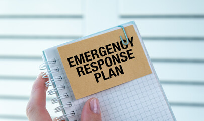 A person is holding a notebook with the words Emergency Response Plan written on it. The notebook is open to a page with a clip holding the paper in place