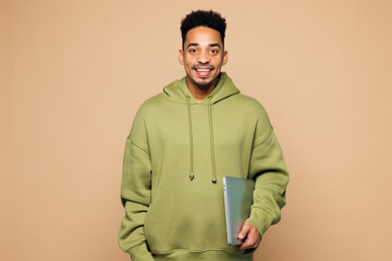 Young smiling happy IT man of African American ethnicity wear green hoodie casual clothes hold...