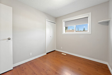 Small, empty room with a wooden floor and a white wall
