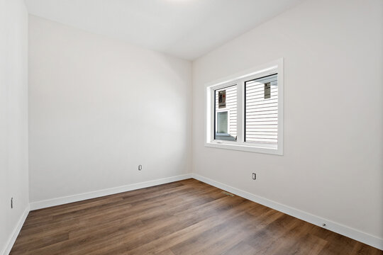 Small, empty room with a wooden floor and a window