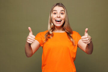 Young shocked surprised happy woman she wears orange t-shirt casual clothes looking camera showing...