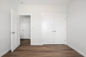 White bedroom with a wooden floor and white doors