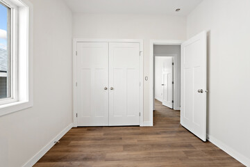 White bedroom with a wooden floor and a window