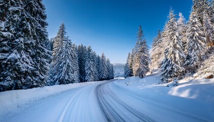 Obraz premium snowy winter road winds through a tranquil snow covered forest under a clear sky