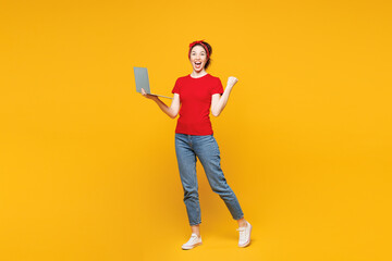 Full body young overjoyed IT woman she wearing red t-shirt casual clothes hold use work on laptop...
