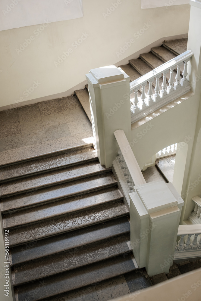 Poster A stunning staircase is illuminated by natural light, featuring a mix of modern and classic elements, creating an inviting atmosphere in a spacious area.