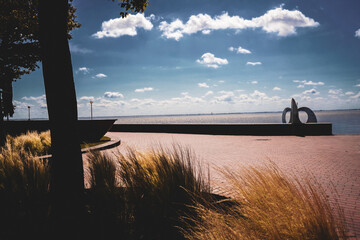 A sunny path with landscape and modern sculpture against a wide sky and the North Sea, on the south beach in 26382 Wilhelmshaven, Germany