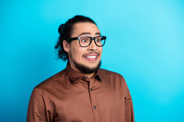Professional young man with a humorous expression in elegant attire standing against a vibrant turquoise background