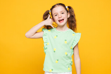 Little toothy cheery cute kid child girl 8-9 years old wears green t-shirt doing phone gesture like...