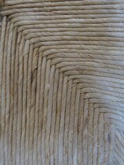 This image shows a detailed woven straw pattern, forming a square spiral design. The natural beige tones and fibrous texture reflect traditional craftsmanship, evoking rustic charm.