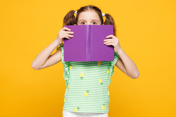 Little shocked amazed kid child girl 8-9 years old she wears green t-shirt hold cover mouth with...