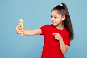 Little kid girl 8-9 years old she wears red t-shirt have fun doing selfie shot on mobile cell phone...