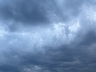 Stormy sky with dark, snowy clouds on a spring day. Clouds are floating across the sky. Dark blue clouds swiftly floating across blue sky. Storm dramatic clouds are floating across the sky. Hurricane.