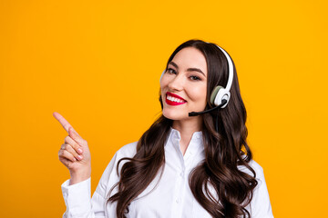Charming young woman in a headset and white shirt making a hand gesture against a vibrant yellow...