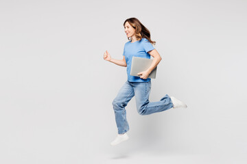 Full body young IT woman she wears blue t-shirt casual clothes jump high hold use work on laptop pc...