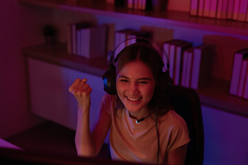 Joyful Gamer Celebrating Win. Young woman in headphones enjoying gaming victory at home.