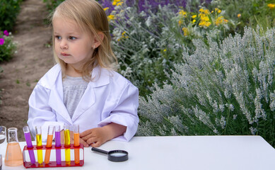 A little girl conducts experiments using test tubes, reagents, and a microscope.
