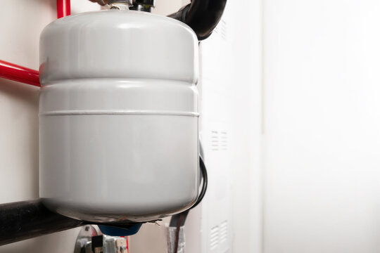 Water expansion tank for hot water heating systems. Close up. Pressurized expansion tank for closed loop hydronic heating system. Known as thermal expansion tank or expansion vessel. Selective focus.