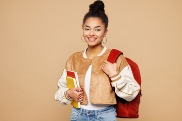 Young smiling happy teen girl student she wear casual clothes backpack bag hold book look camera isolated on plain pastel light beige background studio portrait High school university college concept