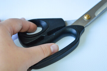 hand holding large metal scissors with black handle  ideal for themes like sewing, crafting,...