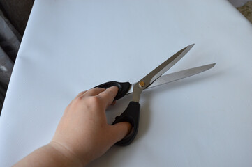hand holding large metal scissors with black handle  ideal for themes like sewing, crafting,...