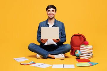 Full body young boy IT student wears jeans casual clothes sit near backpack bag books hold use work...
