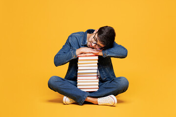 Full body young tired exhausted sad bored boy student wear denim casual clothes glasses sit hold...