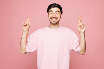 Young man wear t-shirt casual clothes waiting for special moment, keeping fingers crossed, making...
