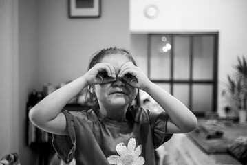 Little girl playing with her hands like glasses