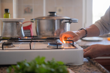 Elderly Woman Turning On the Gas Stove in the Kitchen