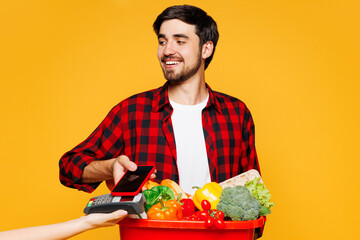 Young man wear casual clothes hold basket takeaway with food products bank payment terminal process...