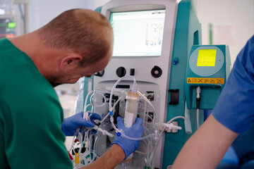Doctor setting up dialysis machine for patient treatment in hospital